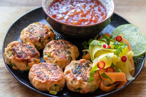 Asian-inspired Thai chicken burgers with dipping sauce on a plate.
