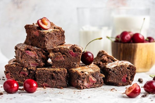 A delicious stack of brownies with cherries on top.