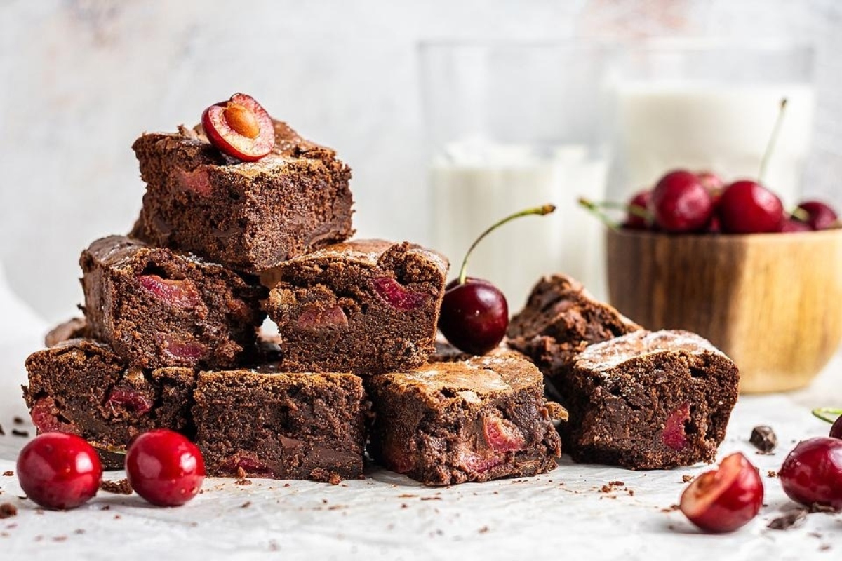 A delicious stack of brownies with cherries on top.