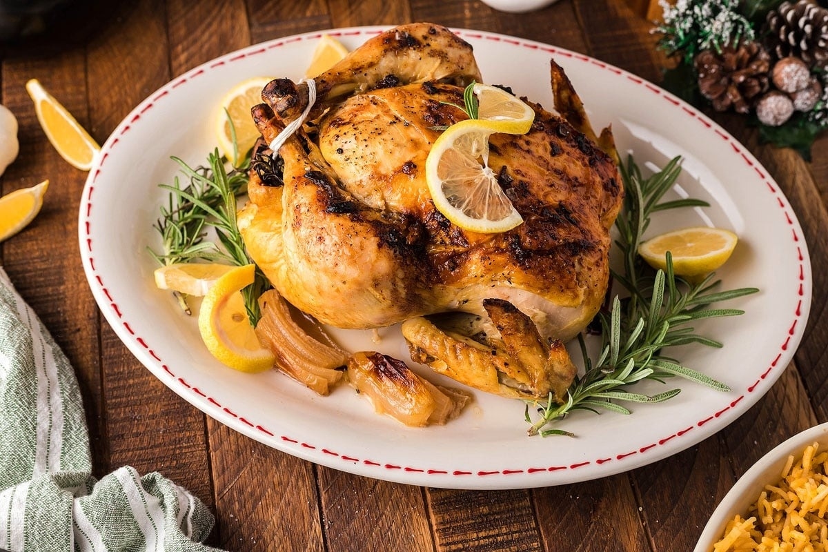 Roasted chicken with rosemary and lemon on a plate.