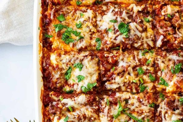Lasagna in a baking dish with parmesan cheese.