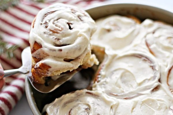 Cinnamon rolls in a pan, generously topped with icing.