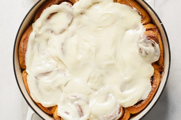 A delicious batch of cinnamon rolls, baked to perfection in a pan and generously topped with creamy icing.