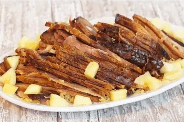 A plate with sliced meat and pineapples on it.