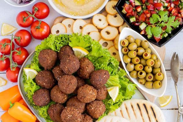 A plate of falafel, tomatoes, olives, and pita bread.