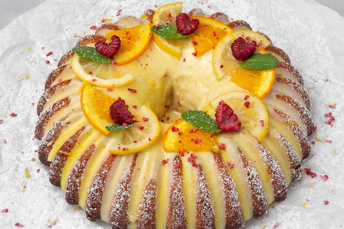 A deliciously moist bundt cake crowned with fresh orange slices and a dusting of powdered sugar.
