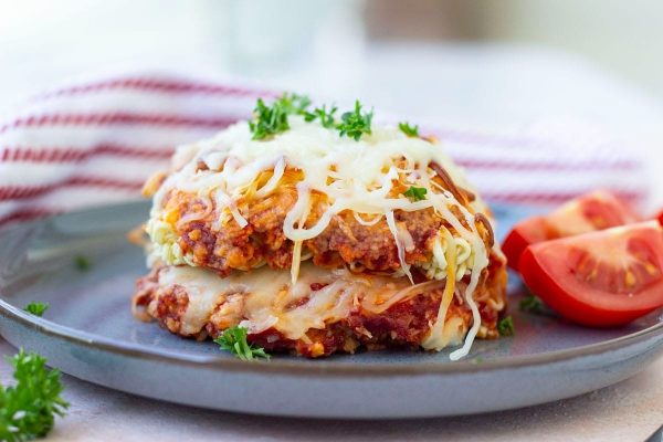 A plate with a pizza topped with cheese and tomatoes.