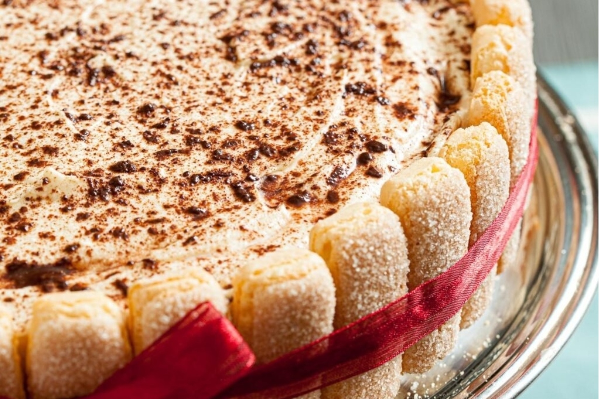 A festive white cake adorned with a vibrant red ribbon, perfect for Christmas celebrations.