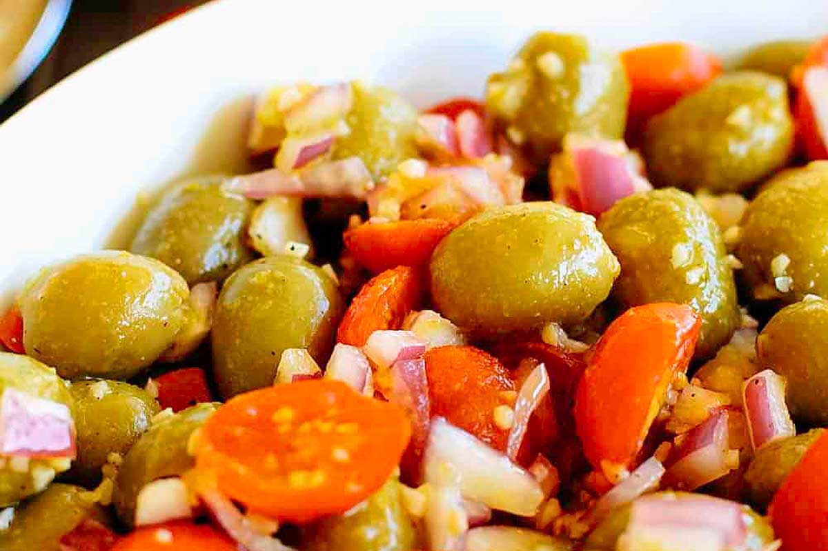 A delicious tomato and onion salad with olives, beautifully presented in a white bowl.