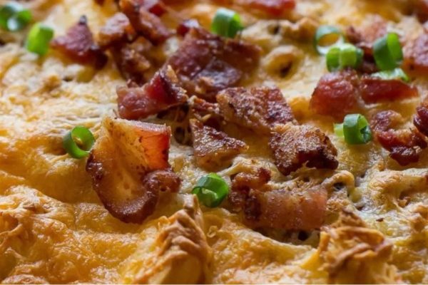 A breakfast pizza loaded with bacon and green onions.