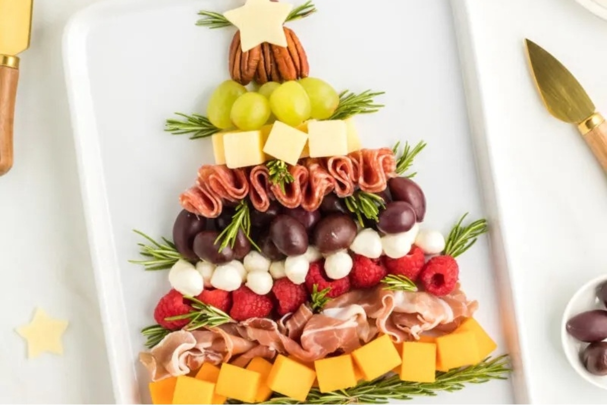A charcuterie board featuring a festive Christmas tree made of cheese and fruit.