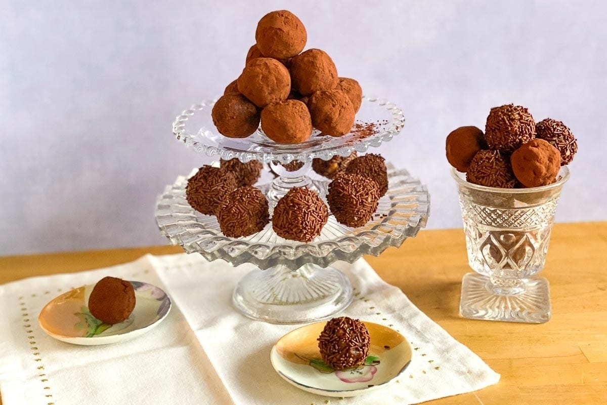 A stack of chocolate truffles, a perfect edible gift for Christmas, elegantly displayed on a glass plate.