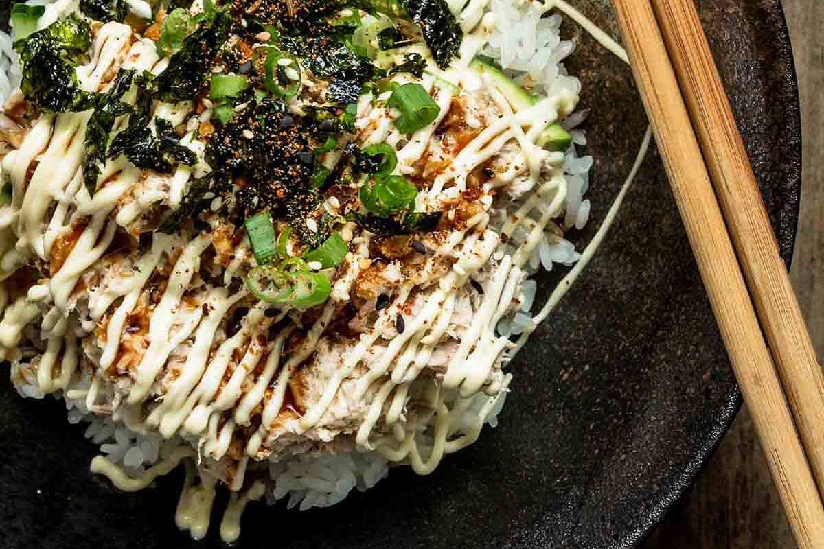 A bowl of rice with sauce and chopsticks.