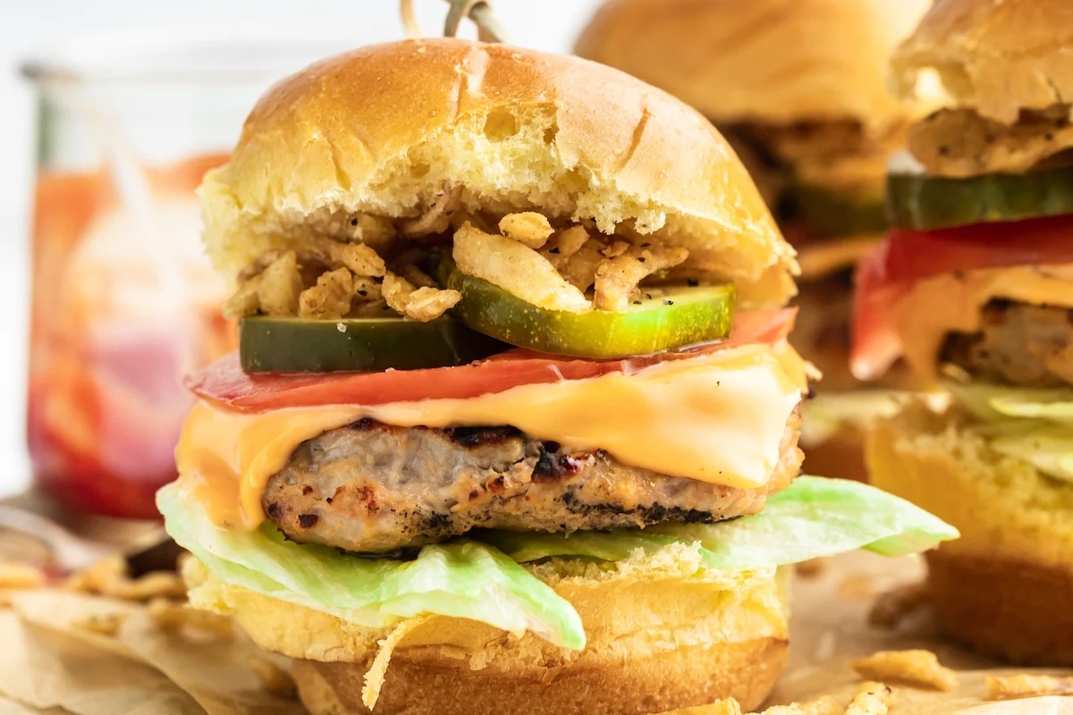 A plate of burgers with ground turkey, lettuce, and tomatoes.
