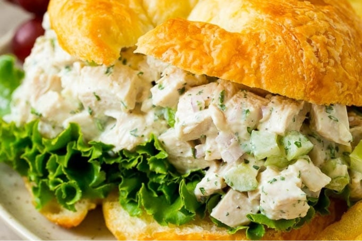 Chicken salad sandwich on a plate with lettuce and grapes, perfect for using up leftover turkey.