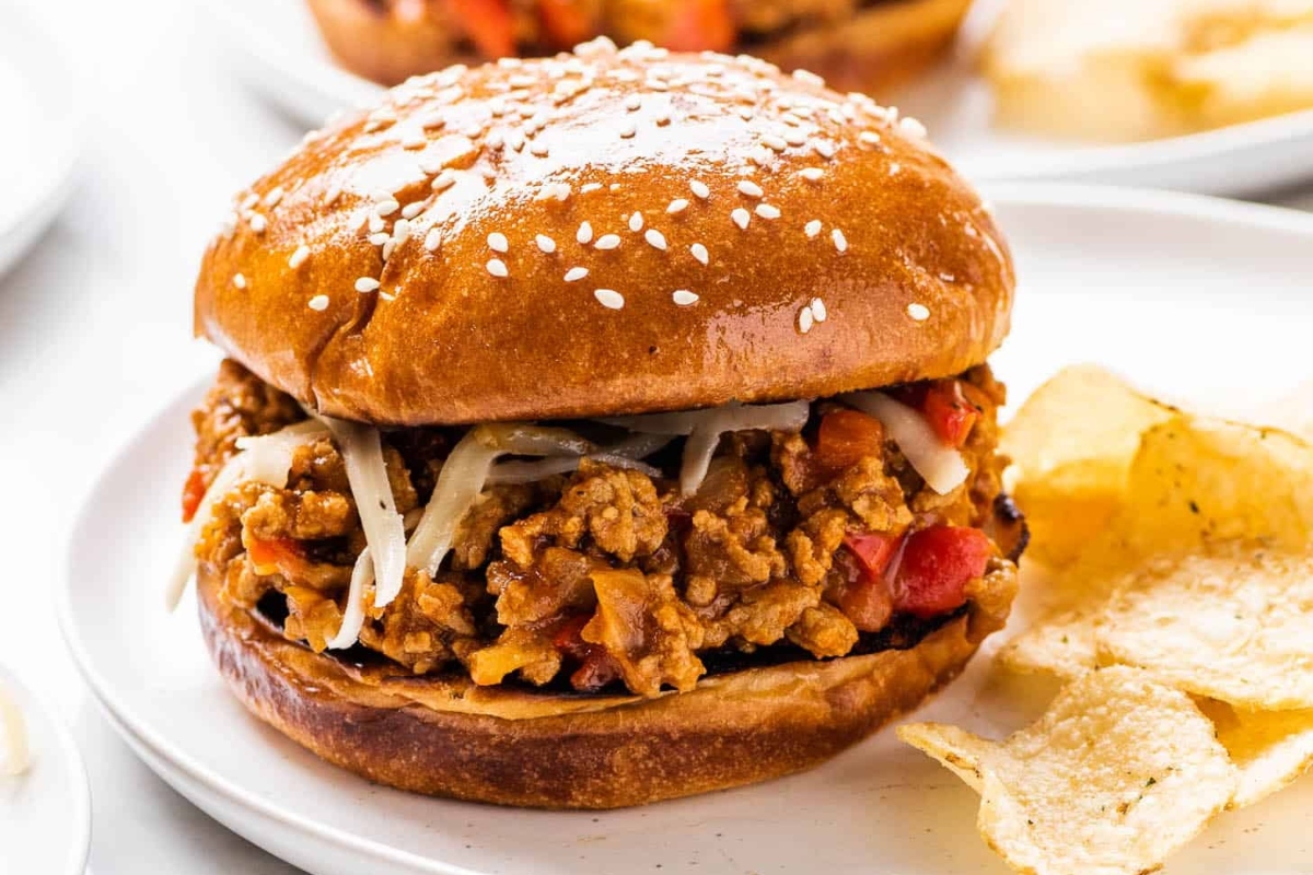A plate of ground turkey burgers and chips on a white plate.