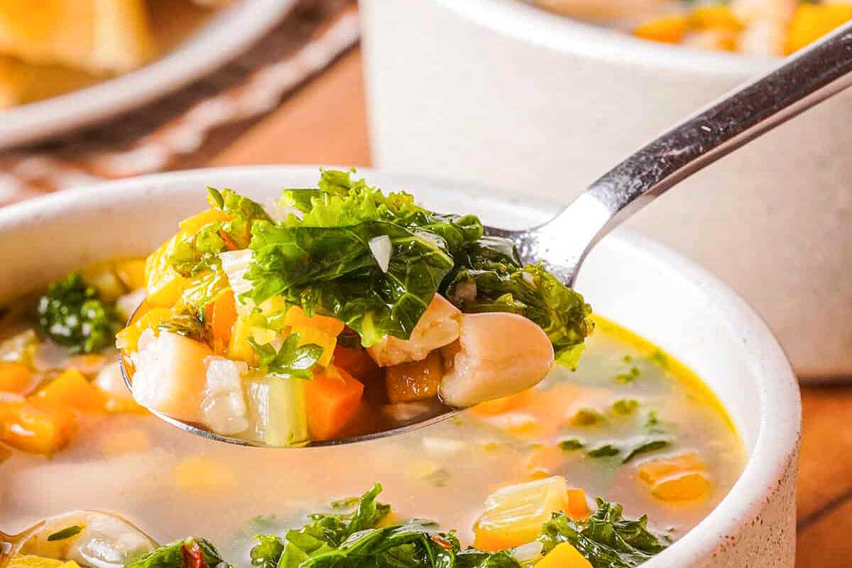 A spoonful of soup with kale and chickpeas.