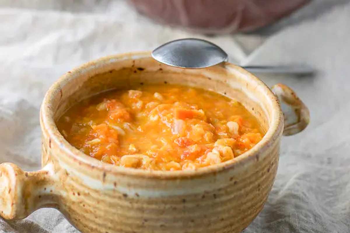 A bowl of carrot soup with a spoon.