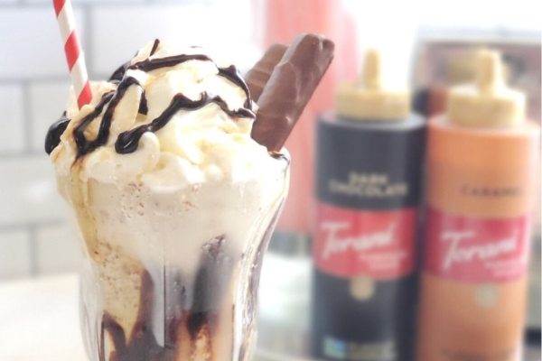 A delicious ice cream sundae drizzled with rich chocolate syrup and topped with fluffy whipped cream.