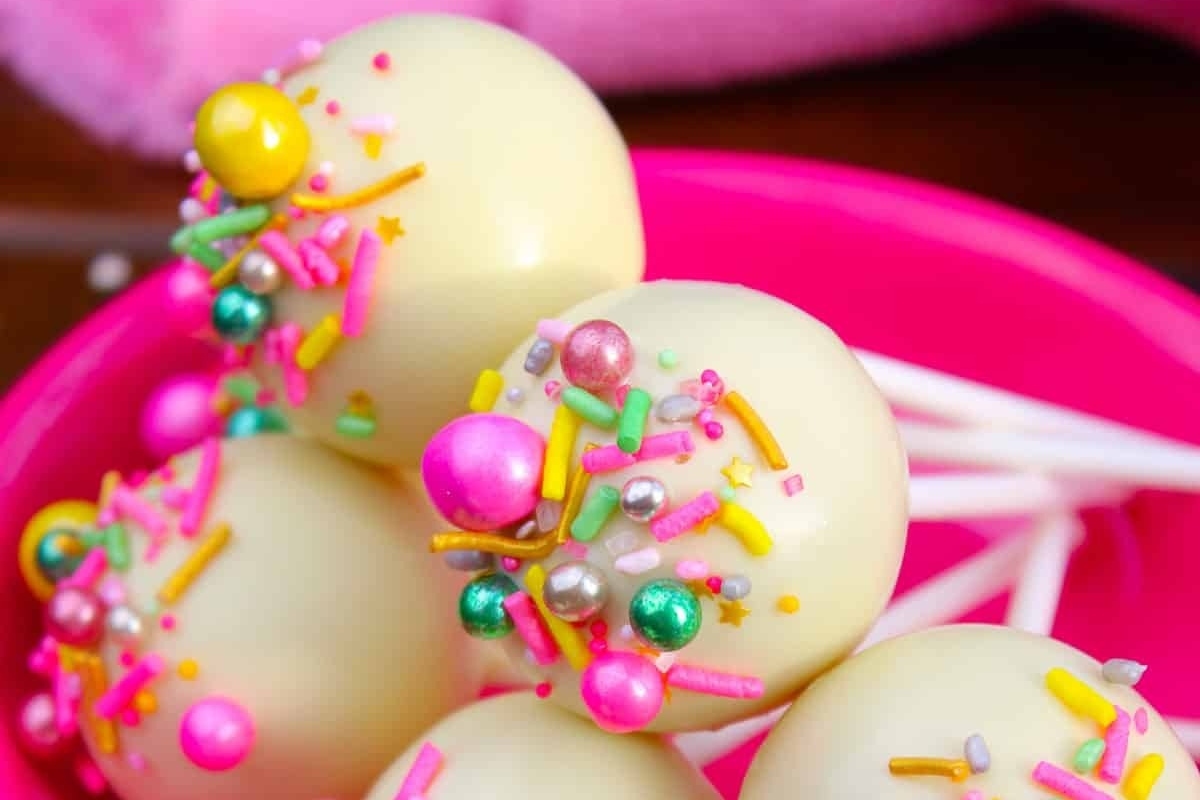 Recipe for white chocolate cake pops in a pink bowl with sprinkles