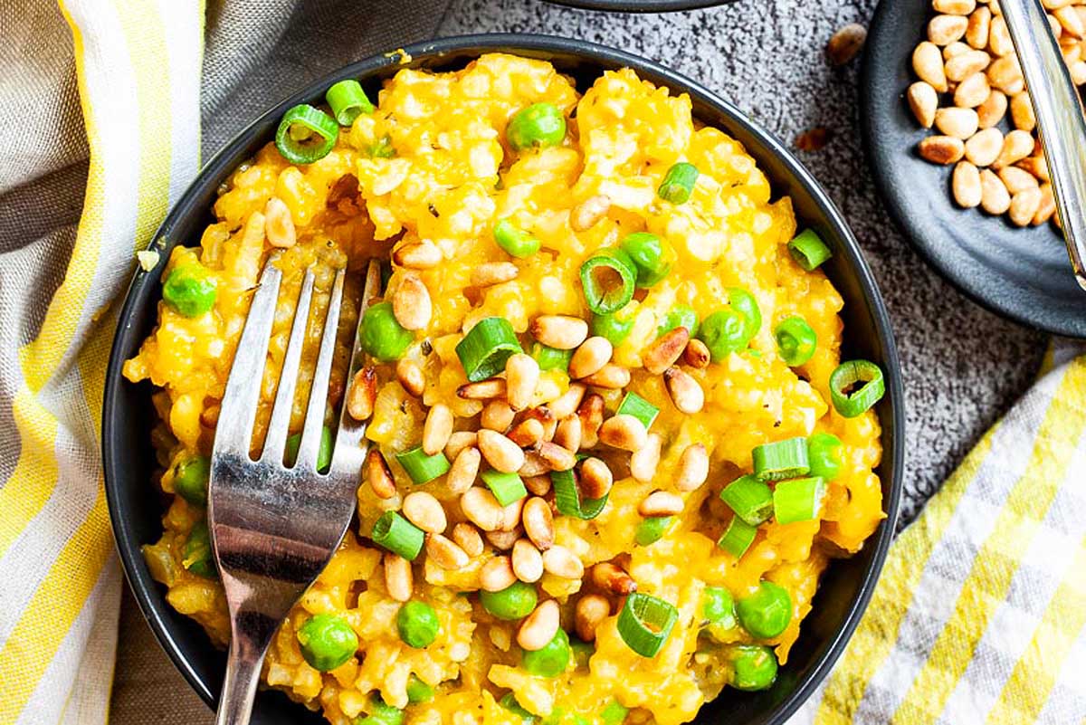 A bowl of risotto with peas and nuts.