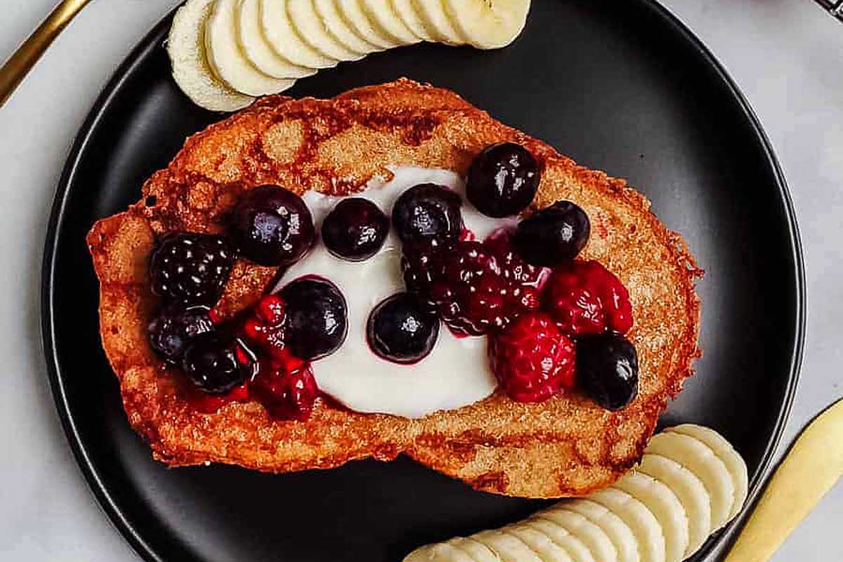 A delightful brunch recipe featuring a plate of French toast adorned with luscious berries and sliced bananas.