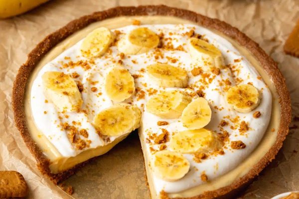 A banana cream pie with a slice taken out.