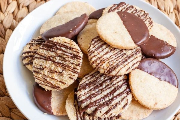 A plate of coconut cookies with chocolate icing on it.