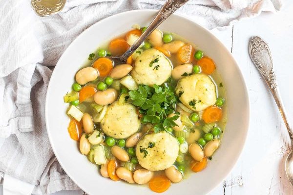 A bowl of soup with dumplings and vegetables.