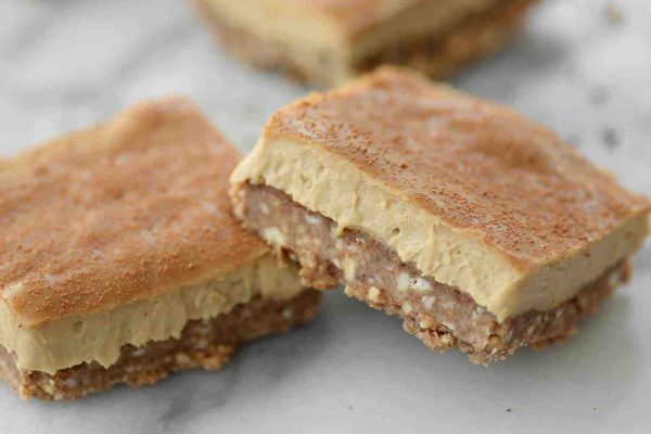 Two squares of peanut butter bars on a marble counter.