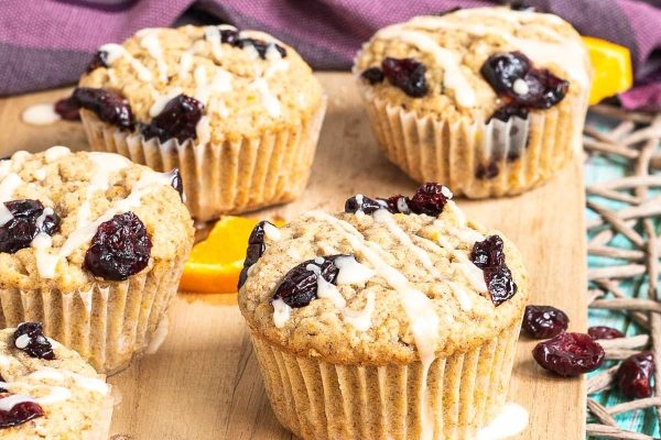 Cranberry orange muffins on a wooden cutting board.