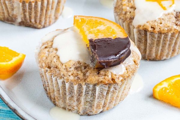 A plate with muffins topped with chocolate and orange slices.