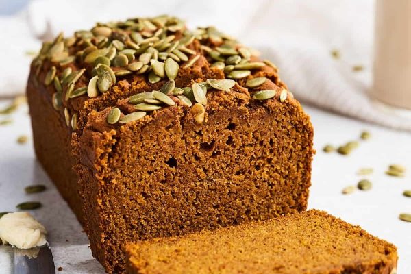 A slice of pumpkin bread with pumpkin seeds on it.