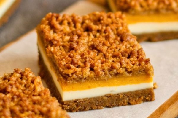 Pumpkin cheesecake bars on a cutting board.