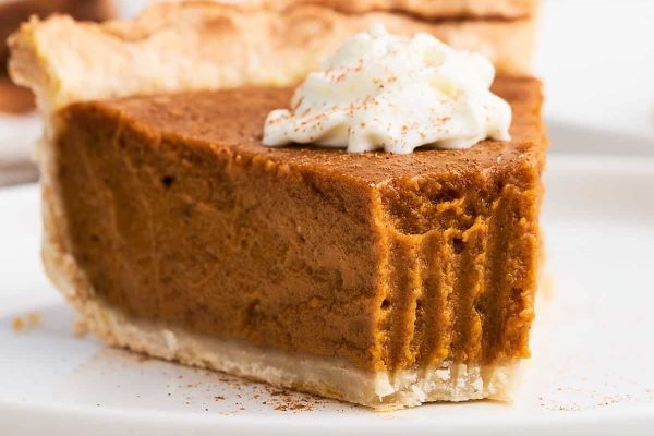 A slice of pumpkin pie on a white plate.