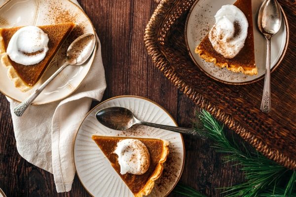 A slice of pumpkin pie with whipped cream on a plate.
