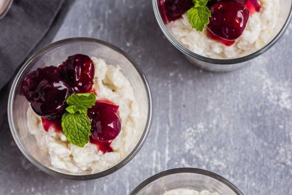A bowl of coconut ice cream with cherries and mint.