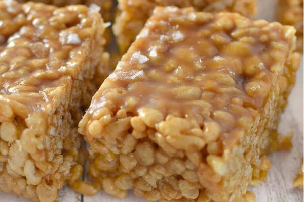 Caramel rice krispie squares on a wooden surface.