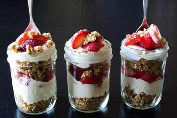 Three jars with strawberries and granola in them.
