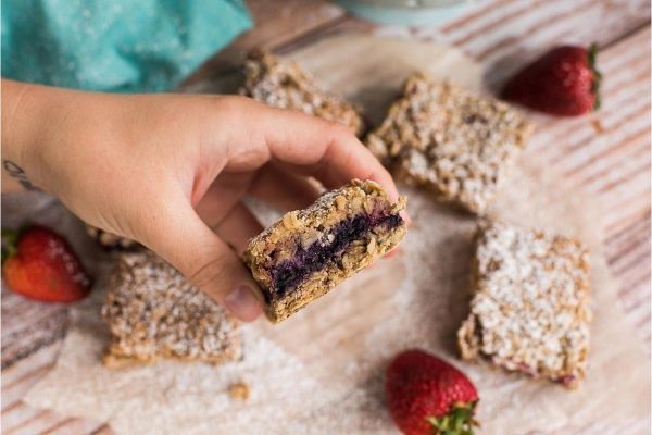 A hand holding a piece of blueberry granola bars.