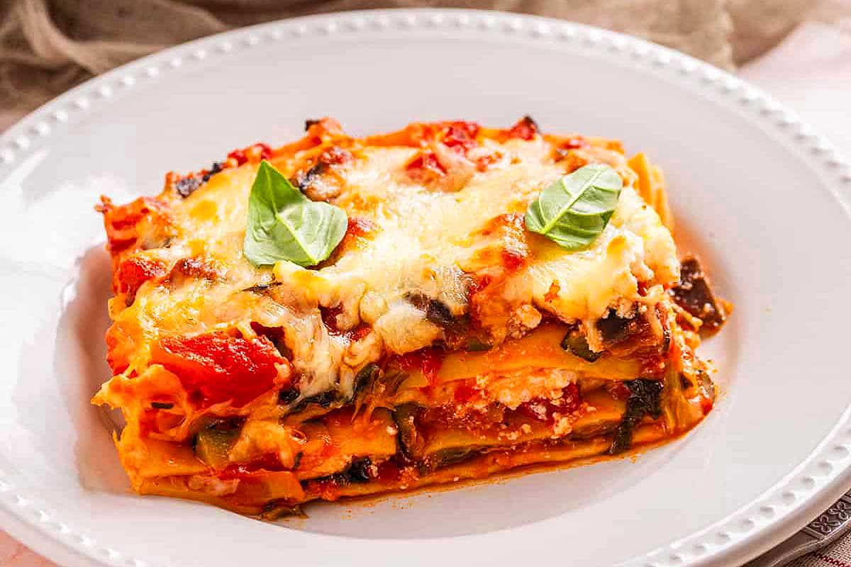 A plate of lasagna with tomatoes and basil.