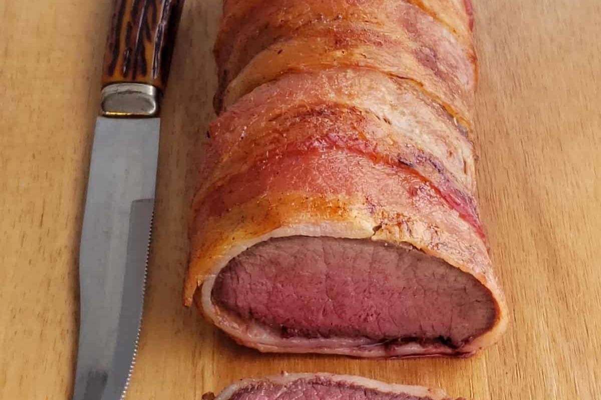 A succulent Thanksgiving turkey on a cutting board with a knife.