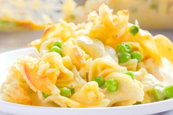 A plate of pasta and peas on a white plate.