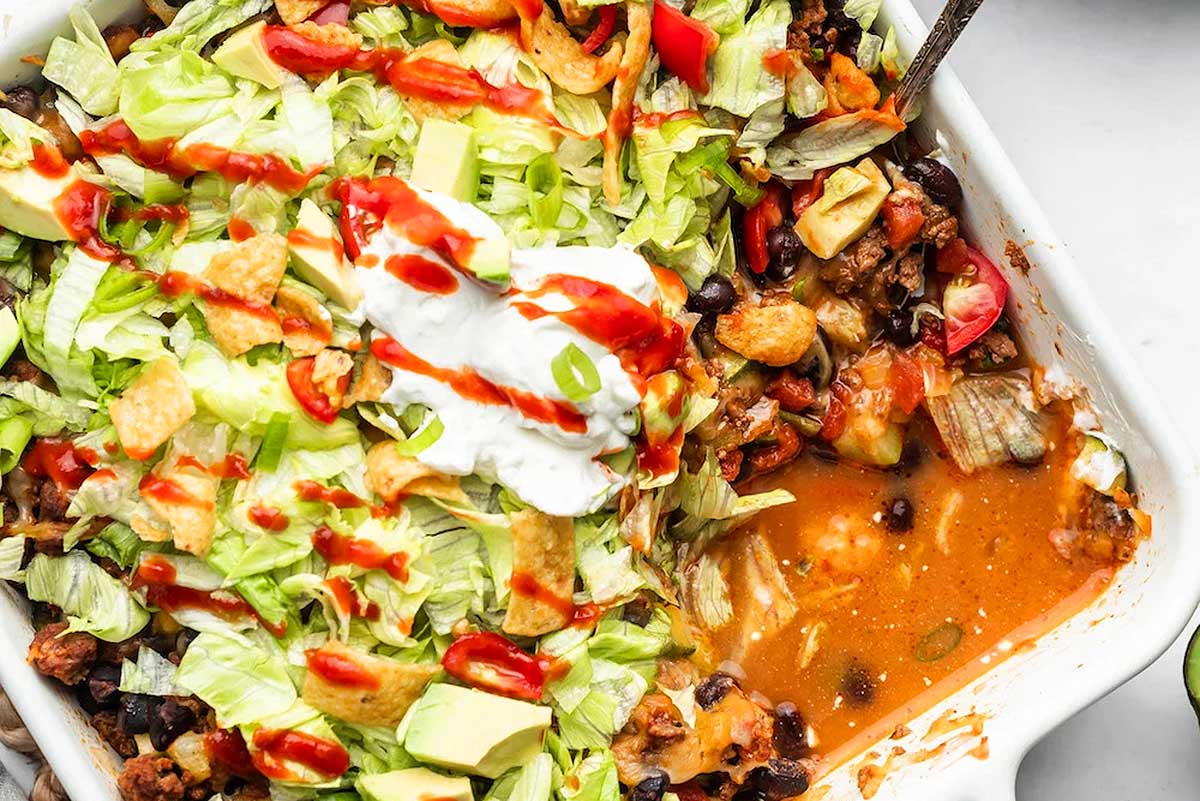 Mexican casserole in a white dish with sour cream on top.