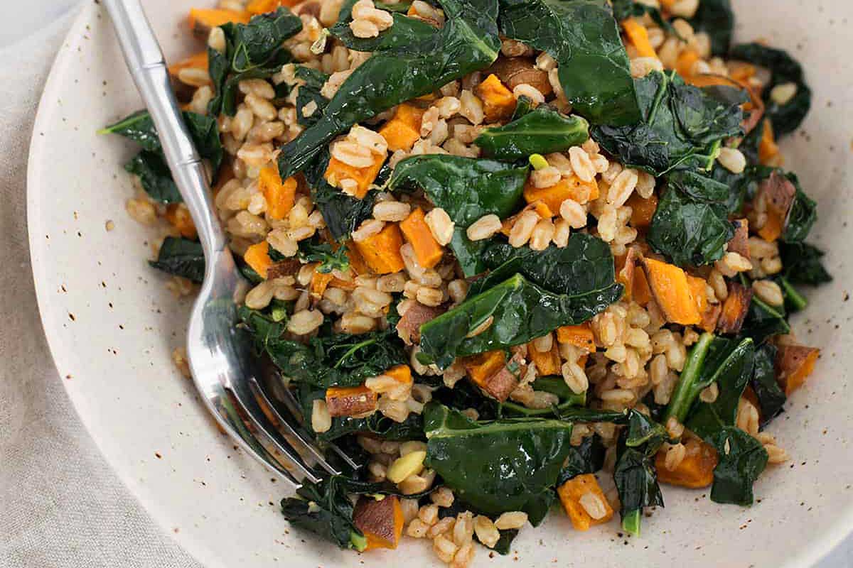 A bowl of farro and kale salad with a fork.