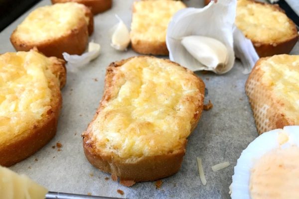 A tray of bread with cheese and garlic on it.
