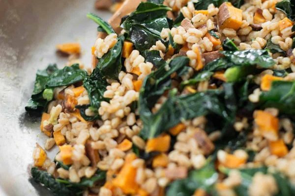 Farro with sweet potatoes and kale in a skillet.