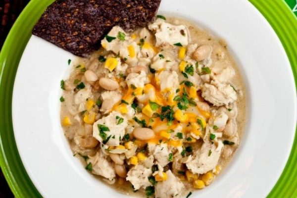 A bowl of chicken and corn soup on a green plate.