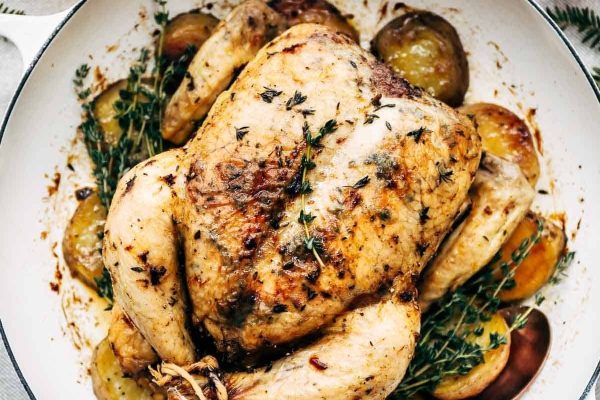 Roasted chicken with potatoes and herbs in a pan.