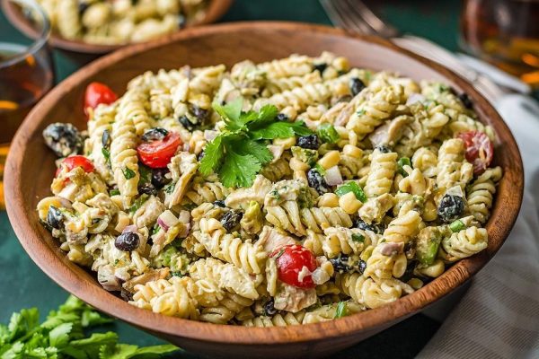 A pasta salad with black olives, tomatoes, and parsley.